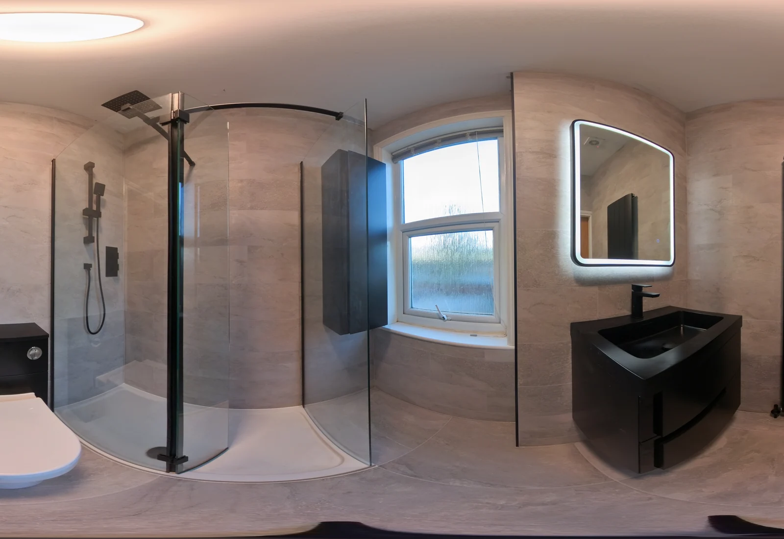 After a bathroom renovation by NM Serv's LTD, with walk-in shower, black vanity and illuminated mirror